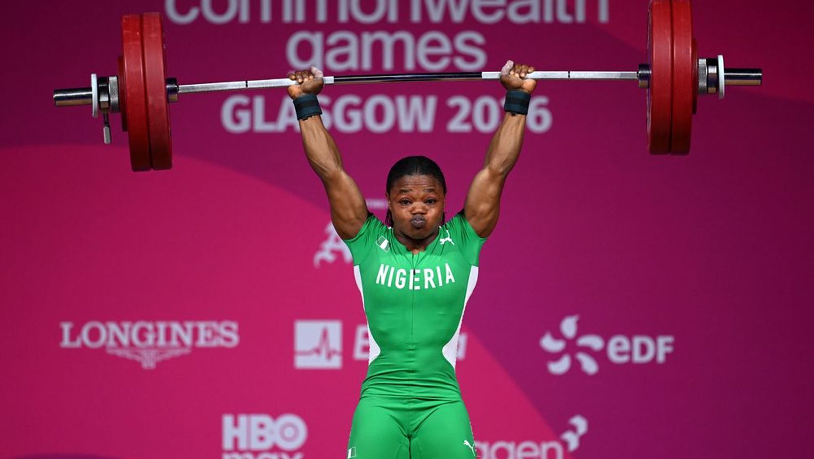 A Nigerian lifter completes a clean and jerk at the Glasgow 2026 weightlifting competition.